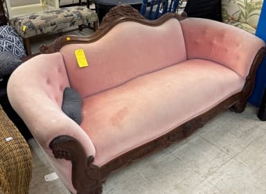 Antique pink loveseat with carved wood detailing sitting inside the ReStore